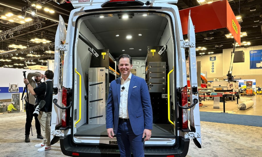 Matt Atkenson poses with an upfitted van on a show floor.
