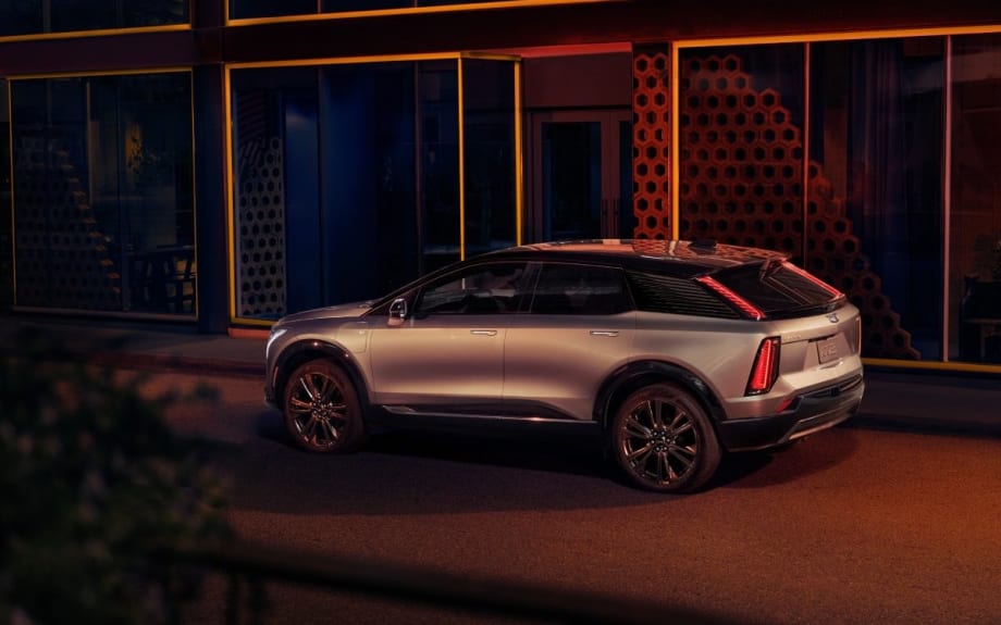 The back and side of a silver SUV at night, parked in front of a building.