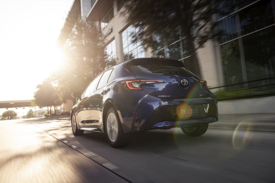 An action shot of a blue 2025 Toyota Corolla Hatchback driving down a city street.