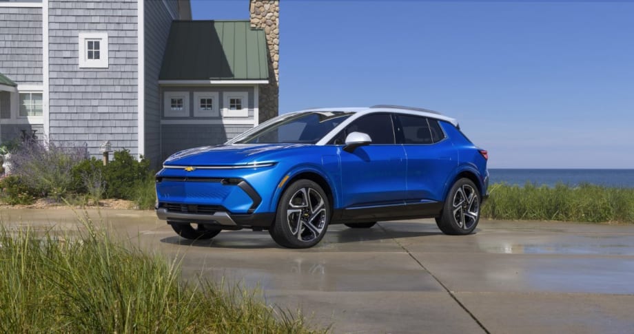 Blue Chevrolet Equinox EV SUV in front of beach house and ocean.