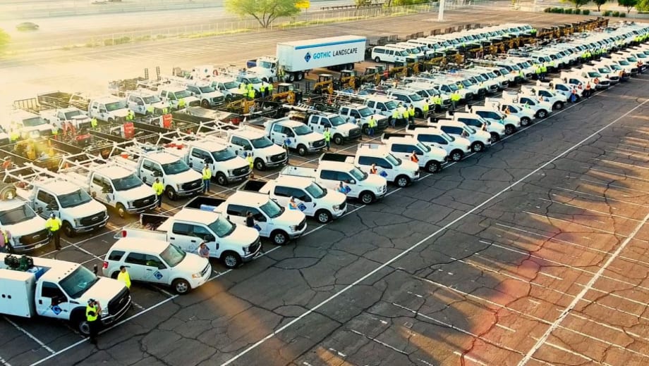 A large group of Gothic Landscape fleet vehicles and personnel pose in a parking lot.
