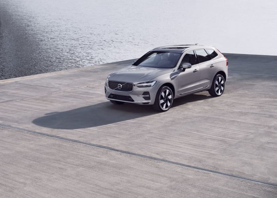 A silver SUV sits on a gray concrete surface with water in the background.