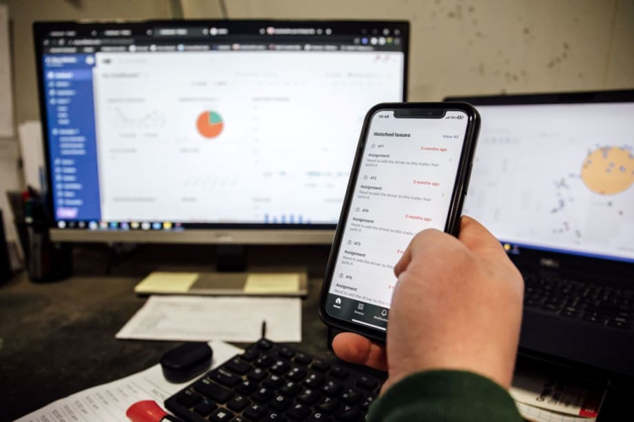 A hand holding a cell phone with fleet information