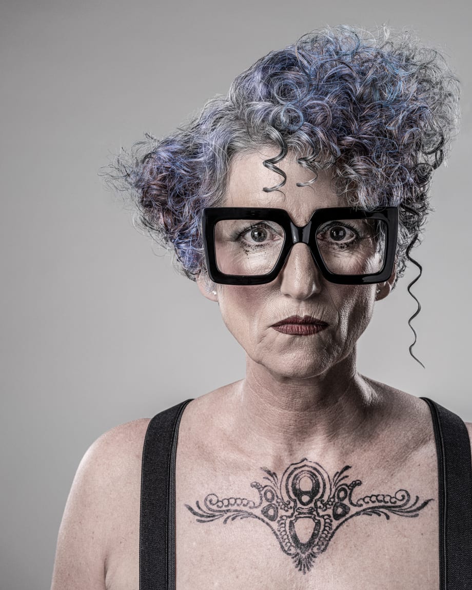 Older woman with big black glasses and short curly hair
