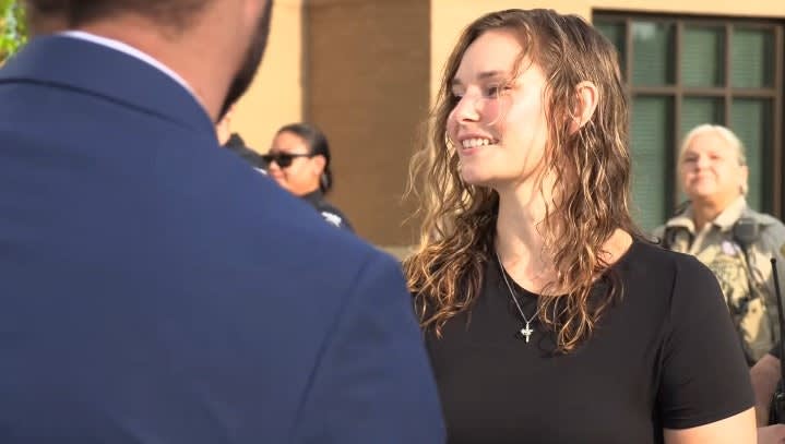 Smiling woman in black shirt talking with person in blue suit outdoors