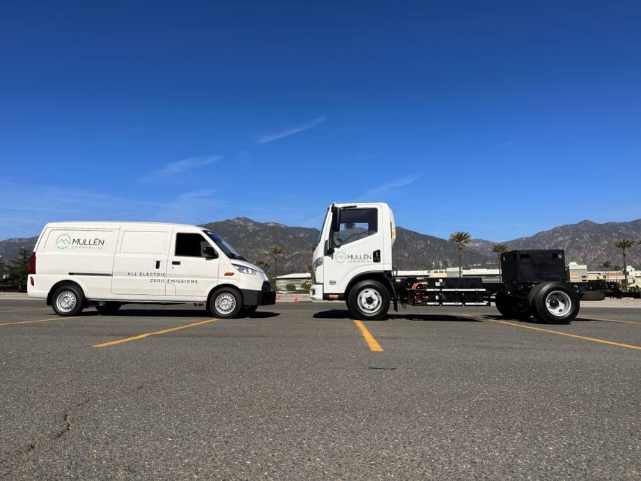 An electric cargo van and a Class 3 cab chassis sit in a parking lot facing each other.