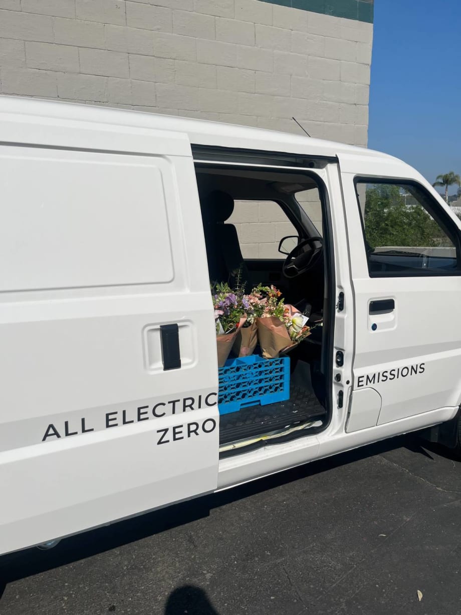 A Class 1 electric cargo van with door open shows flower deliveries.