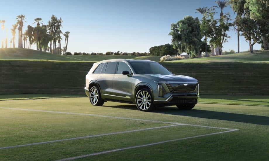A pale green 2026 Cadillac Vistiq parked on a tennis court with palm trees and a blue sky in the background.