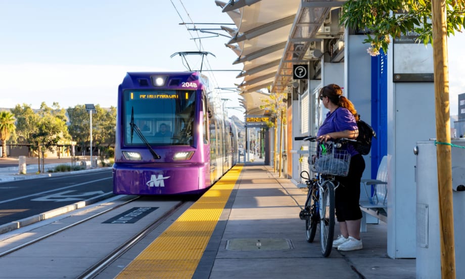A woman with a bike waits on a rail platform for an incoming train.