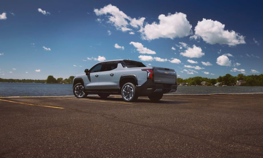 A powder blue 2025 Chevrolet Silverado EV in a parking lot by the water.