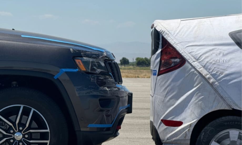 An image of a crash test with a gray car stopping right before hitting a white test car.