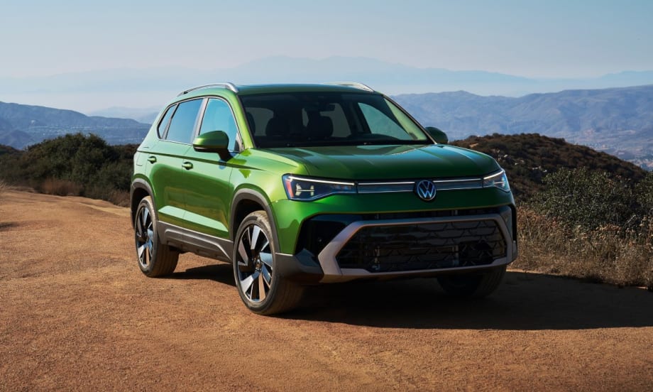 A bright green 2025 Volkswagen Taos parked on a dirt road with mountains in the background.