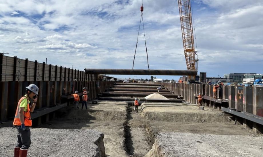 Construction workers guide material hanging from a crane.