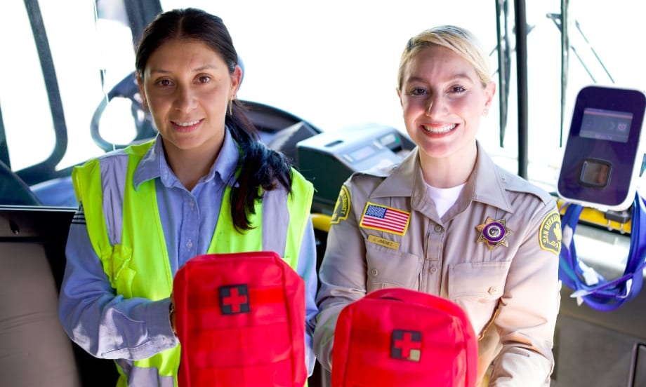 Two female workers hold up NARCAN emergency treatment kits.
