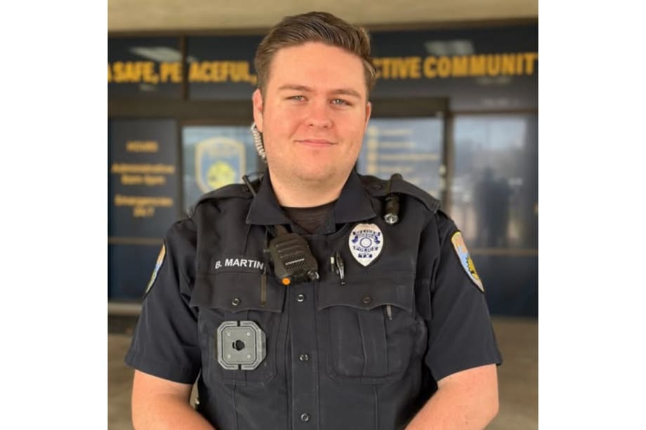 Police officer in dark uniform standing in front of community center backdrop