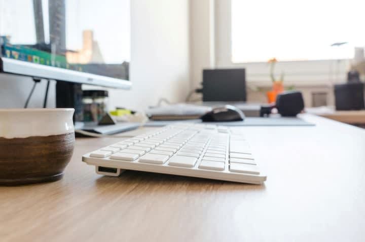 Image of a white keyboard on a wooden desk.