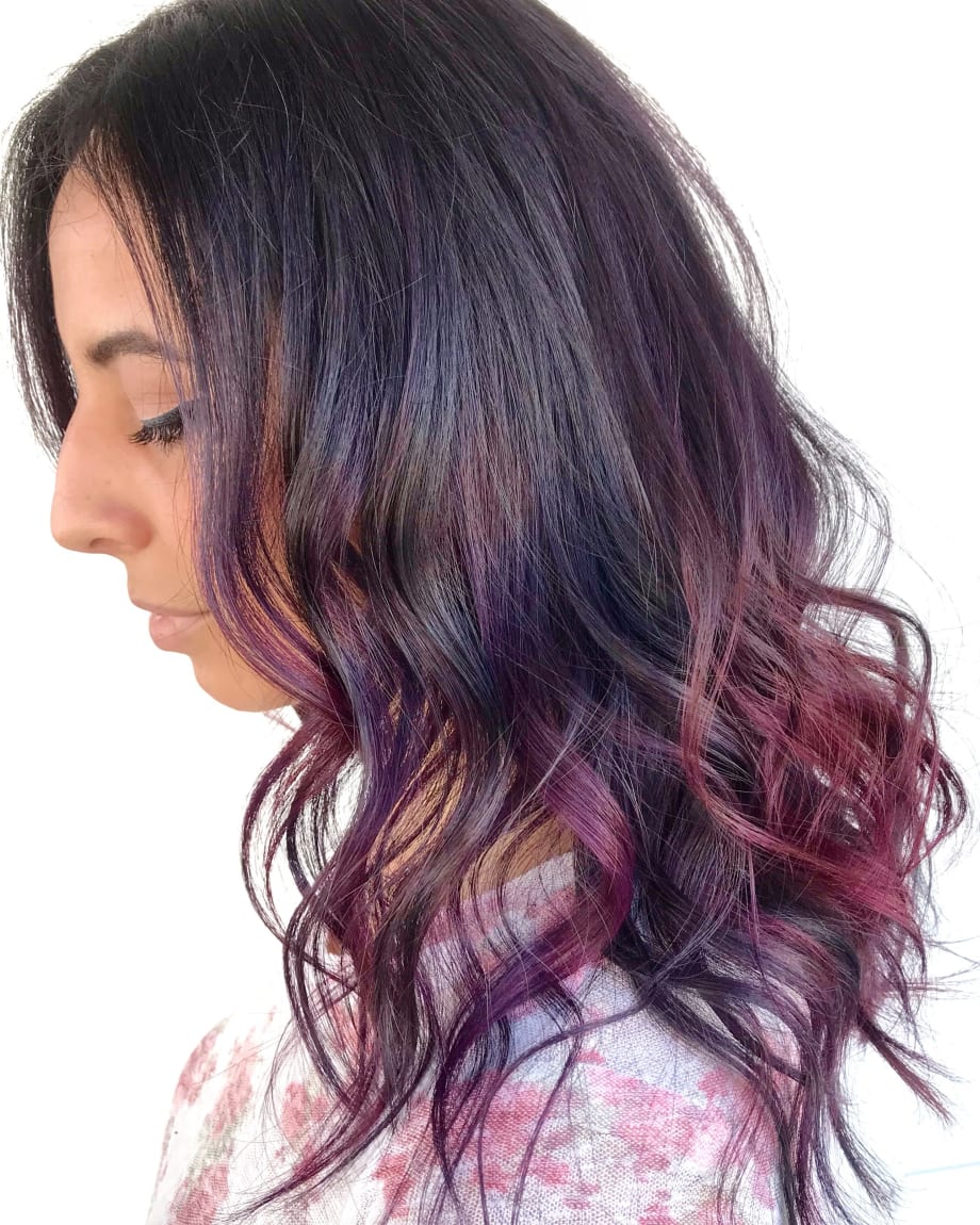 A brunette woman with pieces of bright color throughout her hair.