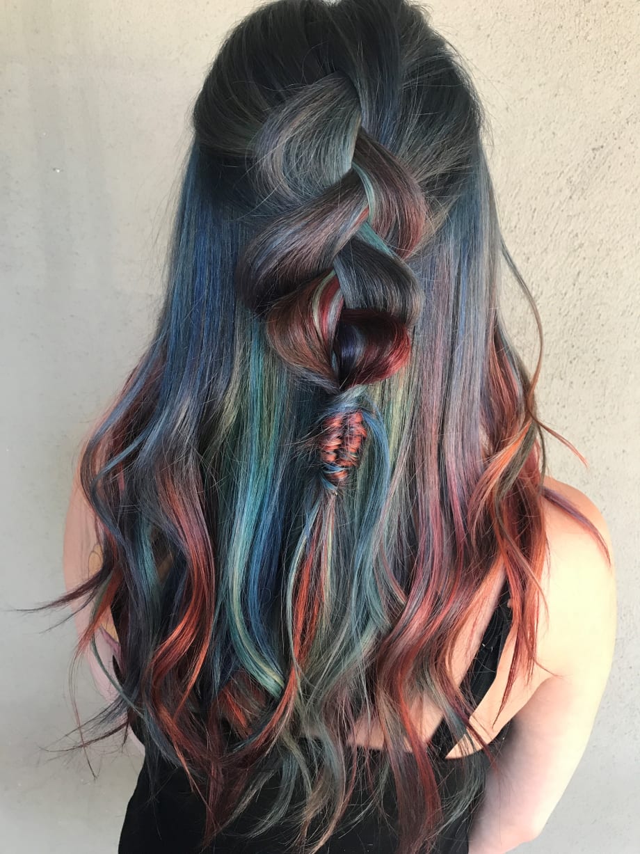 A brunette woman with pieces of bright color throughout her hair.