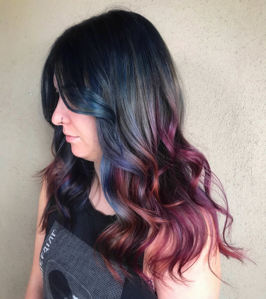 A brunette woman with pieces of bright color throughout her hair.