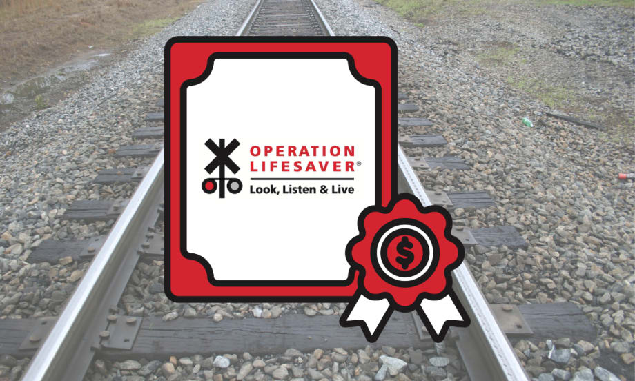 Operation Lifesaver rail safety grant graphic displayed over railroad tracks, highlighting federal funding for crossing safety and trespass prevention campaigns.