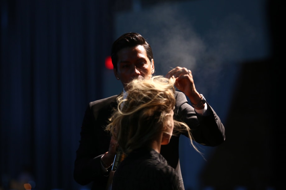A man spraying hairspray on a model