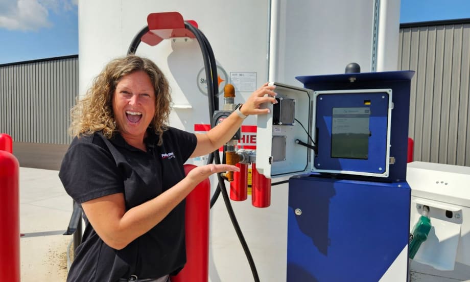 a woman stands in front of fuel tanks