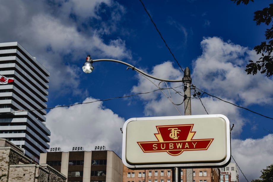A vintage TTC sign against a blue cloudy sky.