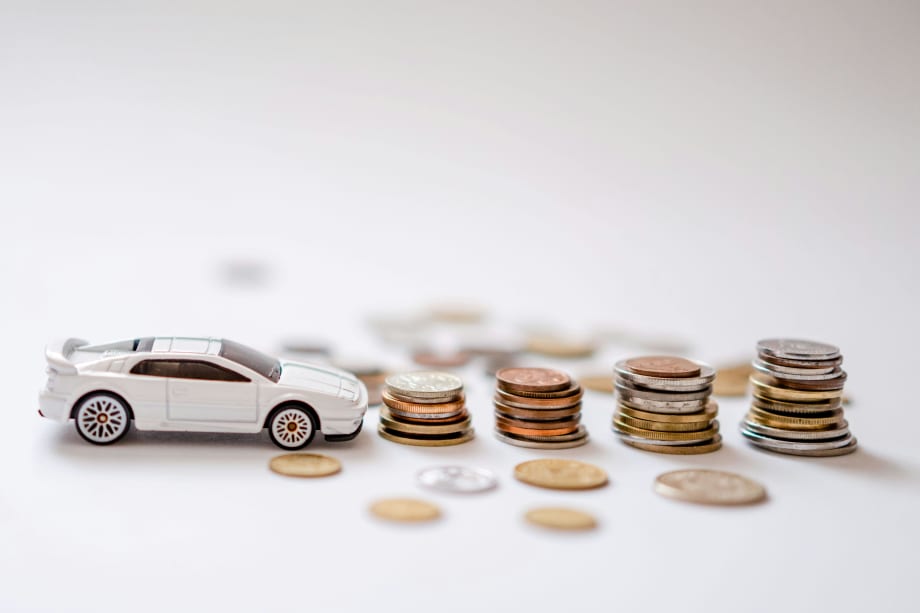Photo of a white toy car next to piles of coins