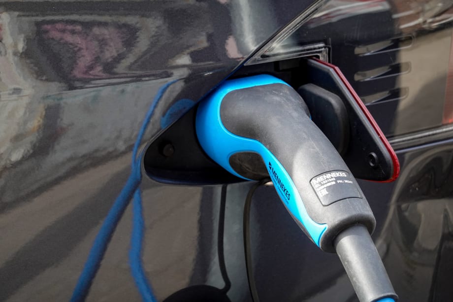 EV charger inserted into dark-colored car port