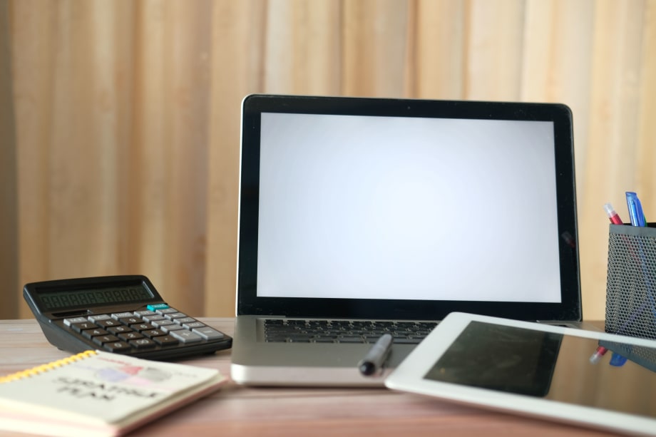 Laptop computer, tablet, calculator and notebook on a desk
