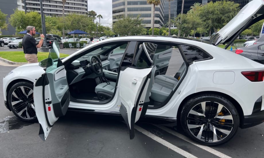 A white Polestar 3 with all doors and trunk lid open while on display at an EV sales event.