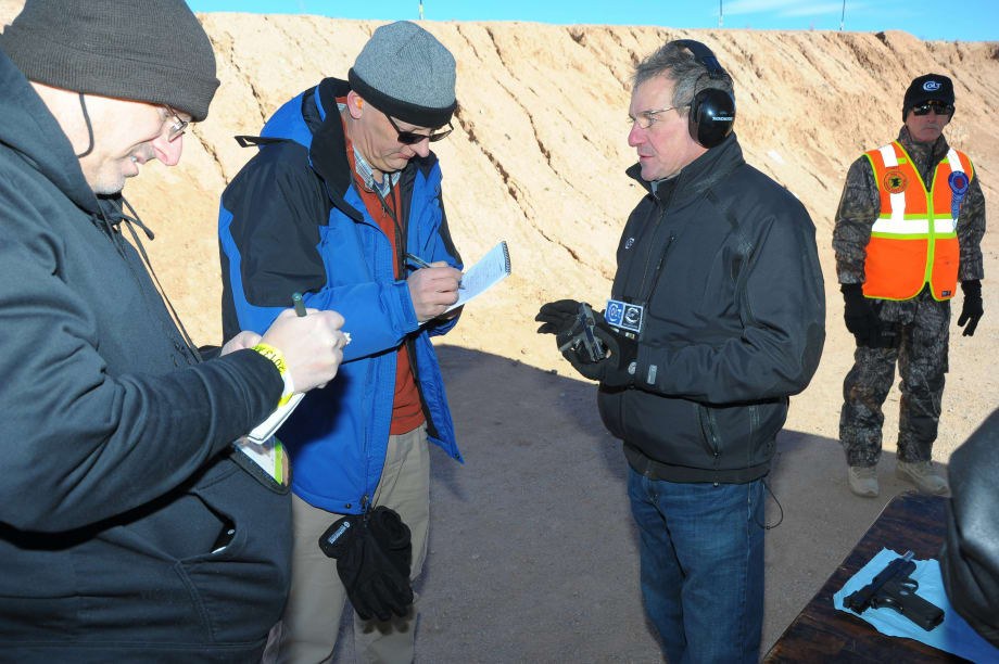 Group of professionals in winter gear examining documents near rocky terrain