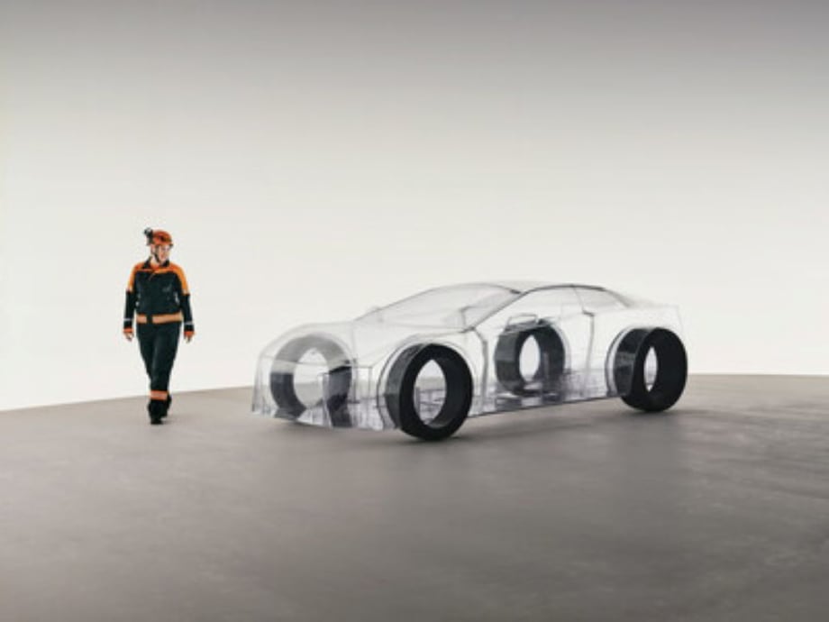 A Sandvik engineer stands beside the transparent eNimon installation, a full-scale model of an electric car made without any metals or minerals, symbolizing the importance of mining for EV production.