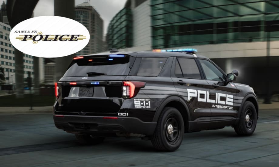 A black Ford Police Interceptor Utility is shown driving down a road.