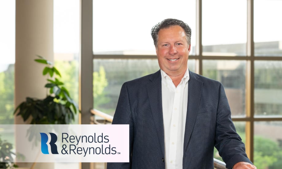 Scott Worthington, vice president of product management at Reynolds and Reynolds, stands indoors in front of large windows wearing a navy blazer and white shirt.