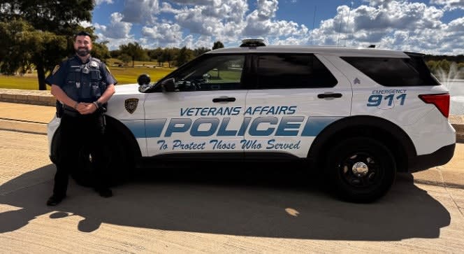 Veterans Affairs Police SUV with officer standing beside white patrol vehicle on sunny day