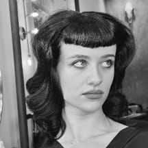 A woman with micro bangs and brunette waves.