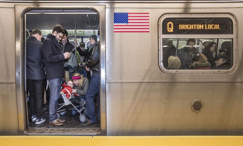 Side view of a subway car with the door open and passengers on board.
