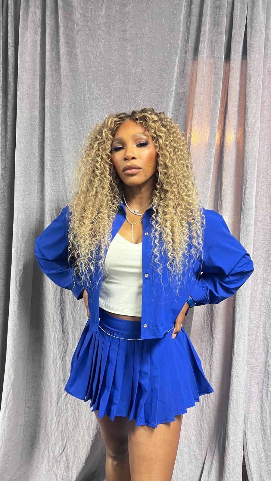 A woman with long curly hair, standing.