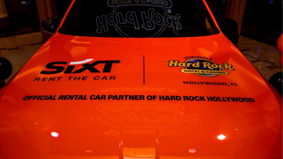 A red hood of a car with SIXT and Hard Rock logos.