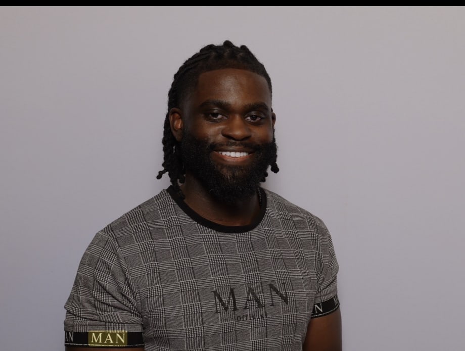 A man with dark hair and a beard, smiling.