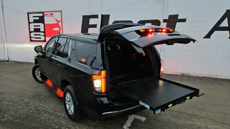 Black SUV with open rear hatch and extended cargo slide-out platform