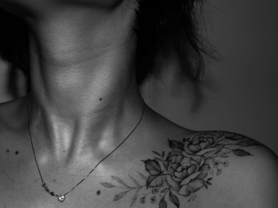 A photo of a flower tattoo on a shoulder of a woman.