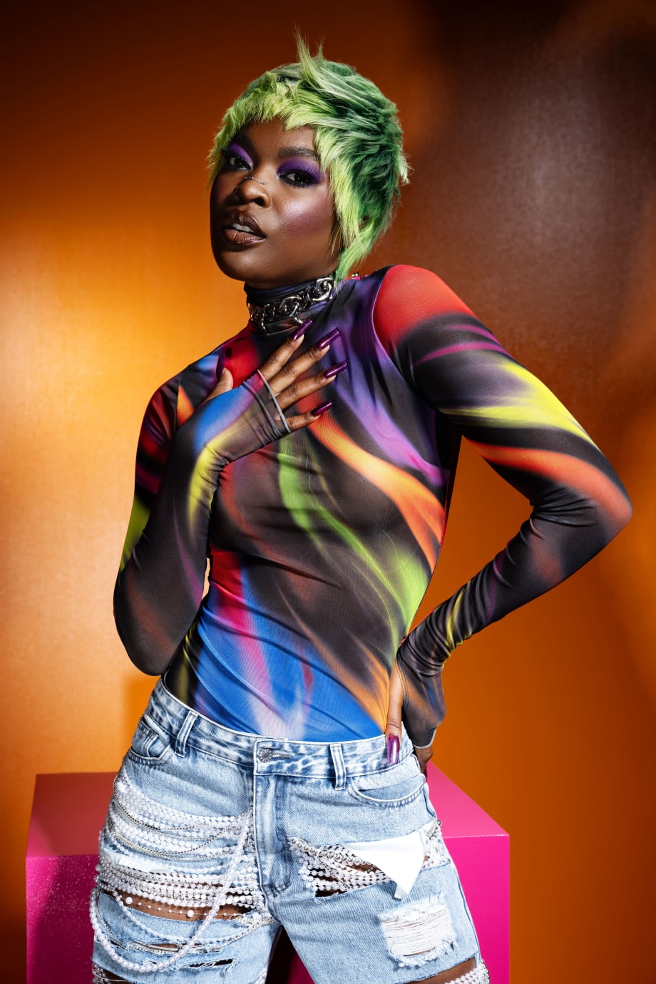 A Black female model with short green hair.