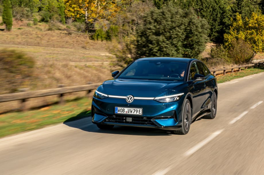 A blue Volkswagen ID.7 with a European plate is seen driving along a highway.