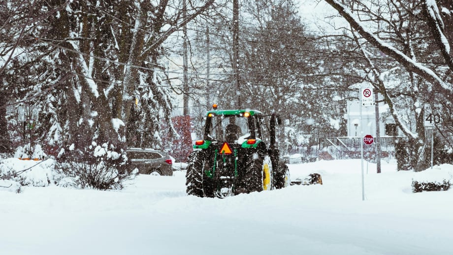 A snow plow in the winter while it snows