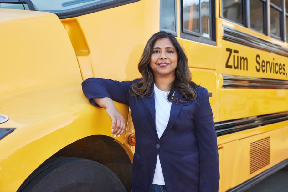 A woman stands in front of a school bus