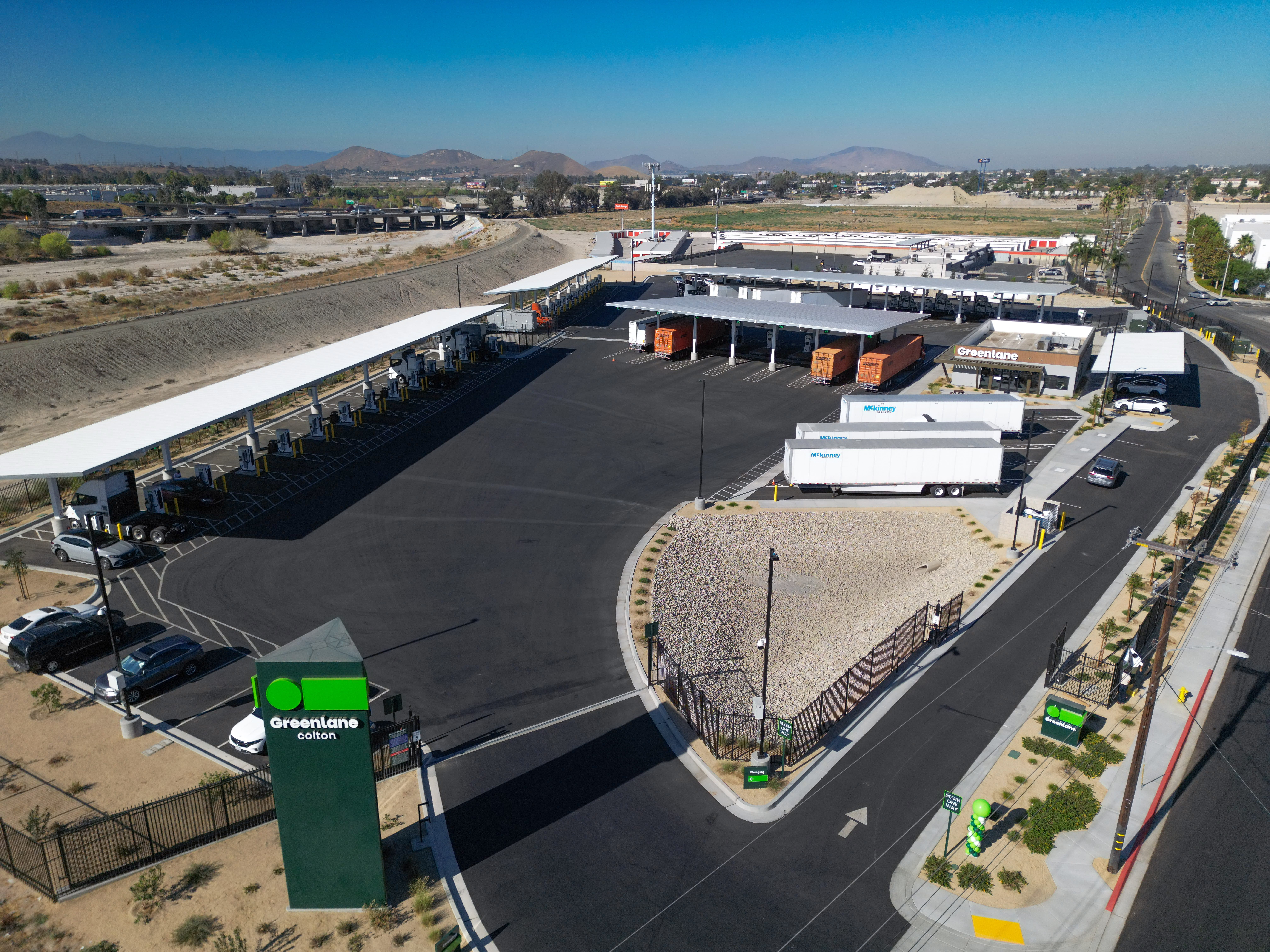 Aerial view of a Greenlane EV charging center with trailers lined parking opposite large covered parking canopy.
